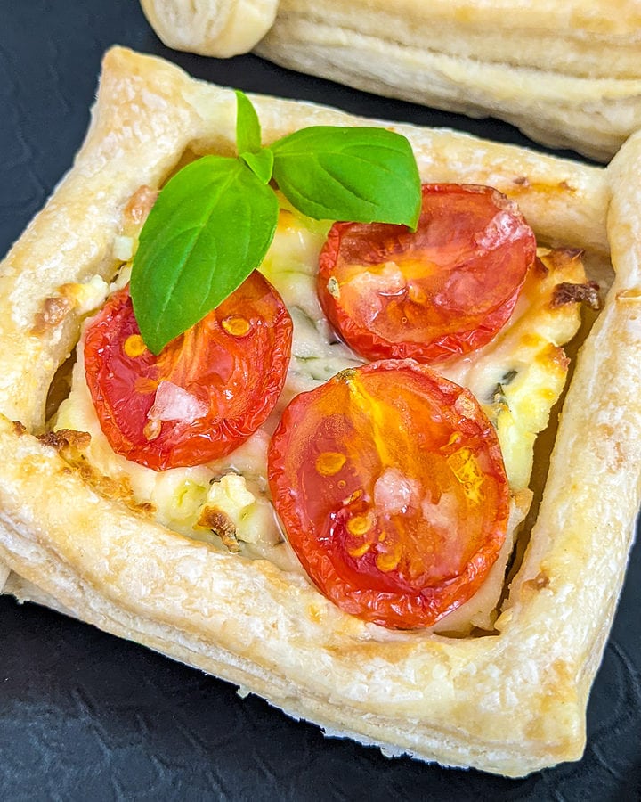 Close look of tomato tartlets with cream cheese and basil leaf,