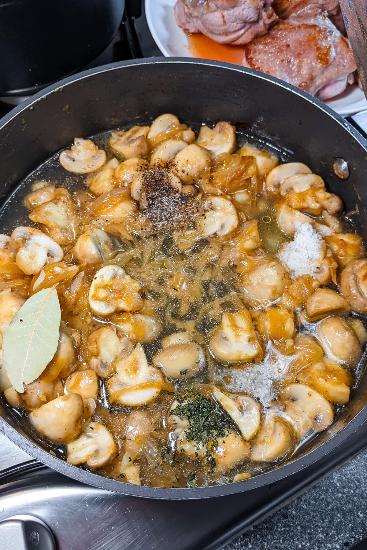 Adding spices and bay leaf over the fried mushrooms and fried onions.