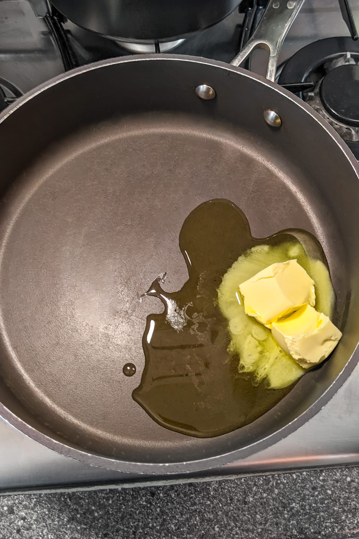 Melting butter in a frying pan on a stove.