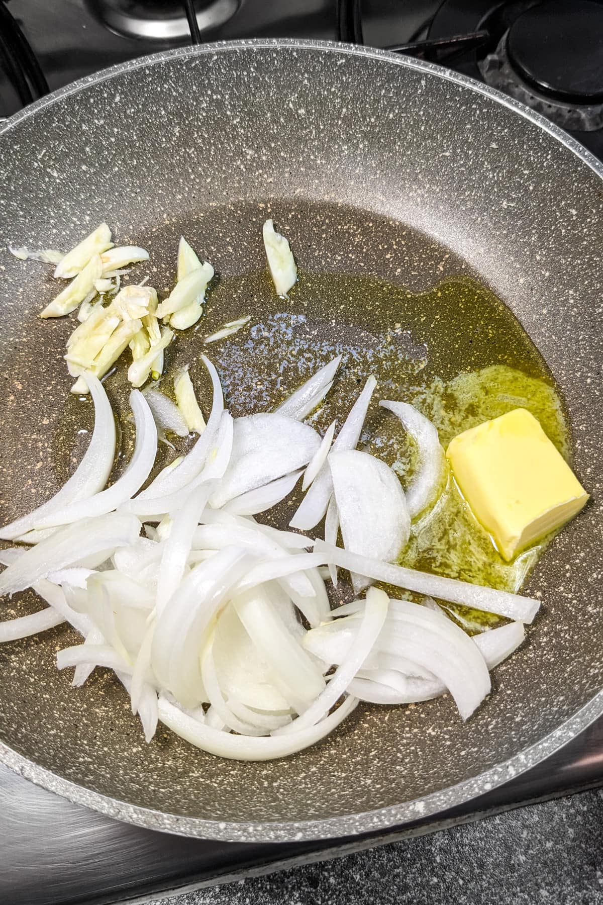 Frying chopped onions and garlic in a piece of butter.