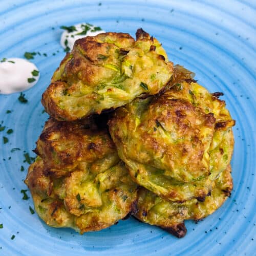 Close look of zucchini garlic bites with sour cream and chopped parsley.