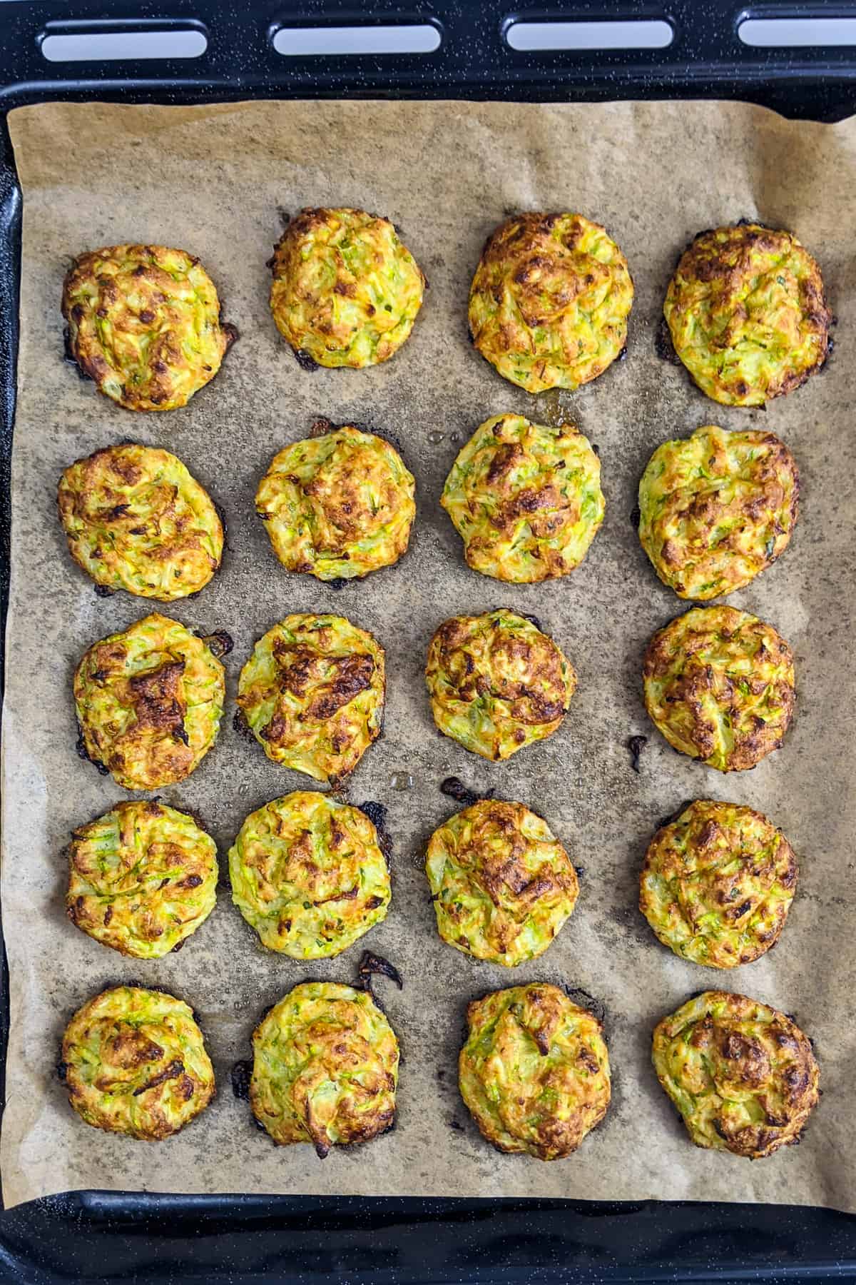 Cooked zucchini garlic bites on a baking tray covered with baking paper.