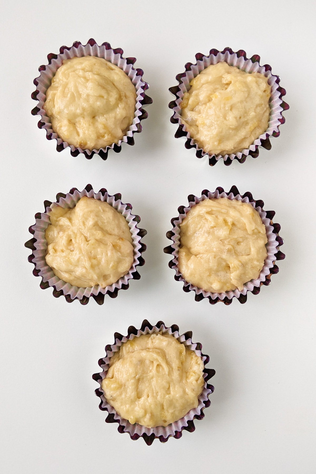 Top view of 5 banana muffins on a white table.