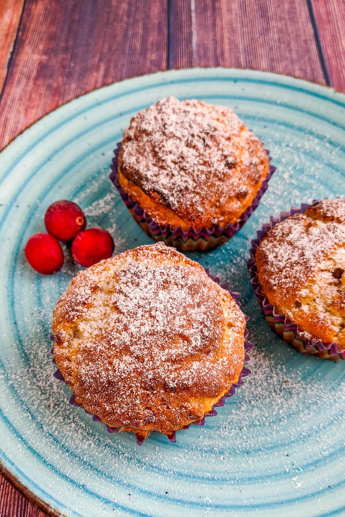 3 Banana muffins on a blue plate on a wooden table.
