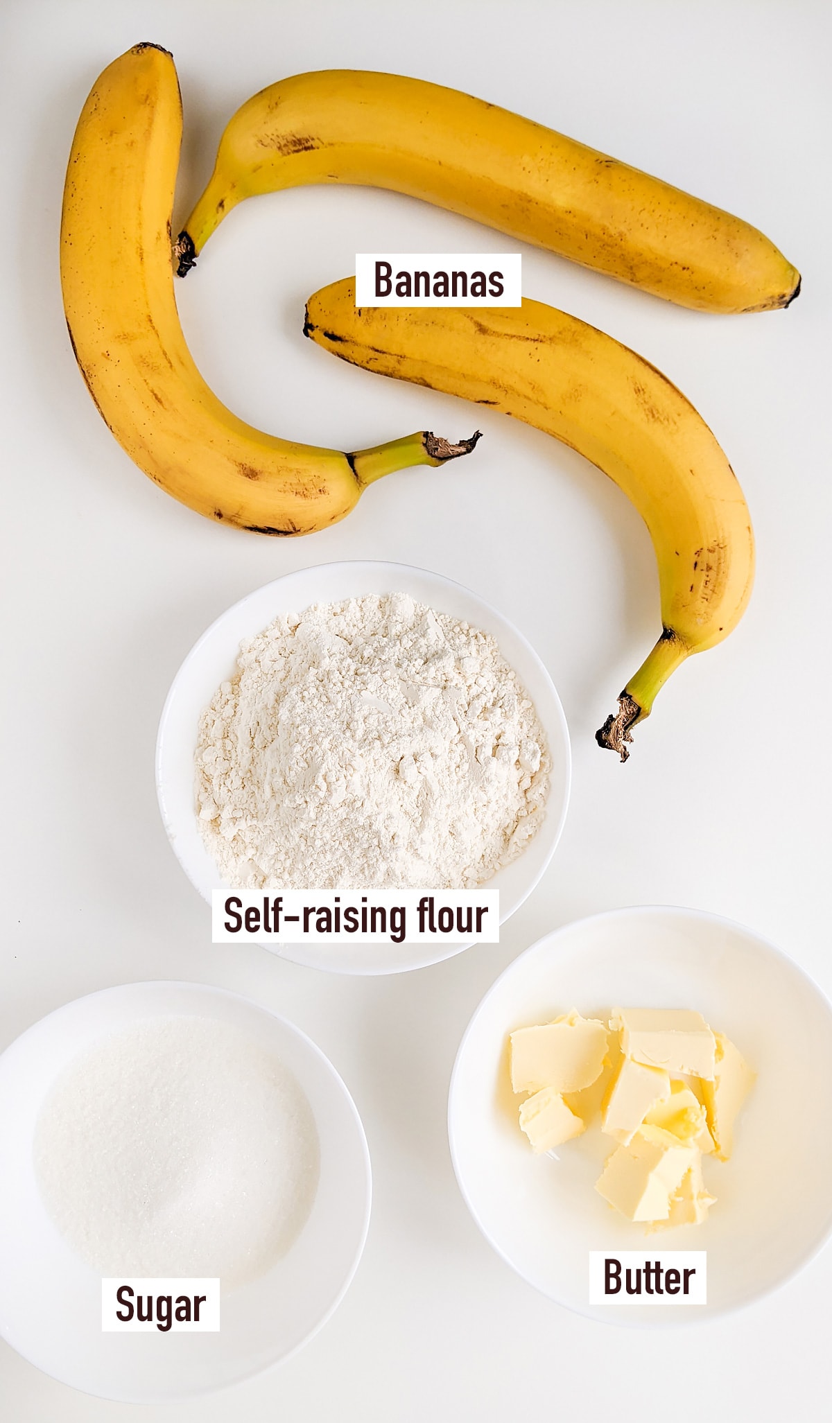 3 ripen bananas near a plate with flour, powdered sugar and butter.