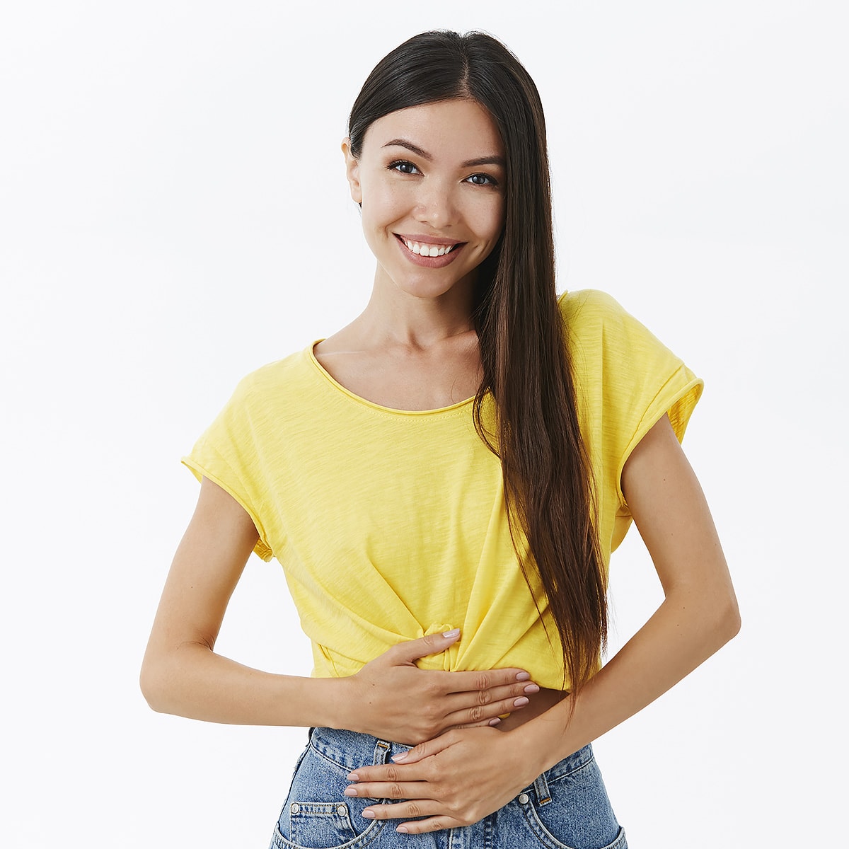A cheerful girl in a yellow t-shirt holding her stomach.