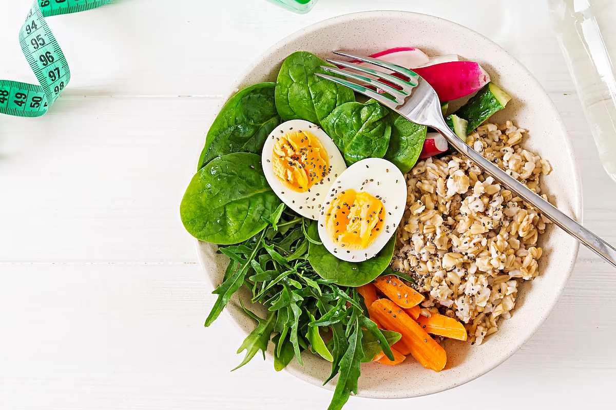 Top view of a plate with an boiled egg, greens and oats.