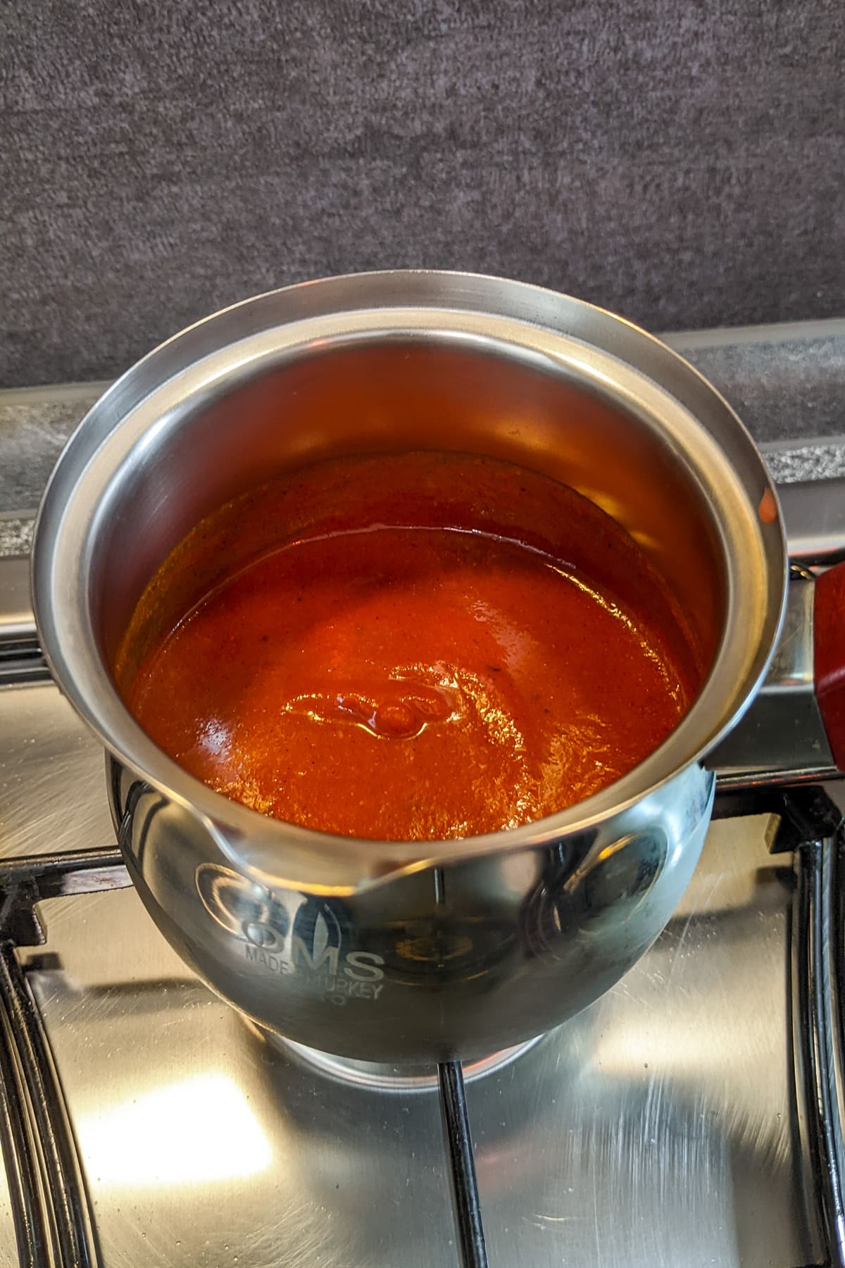 Close look of a saucepan with homemade BBQ sauce on the stove.