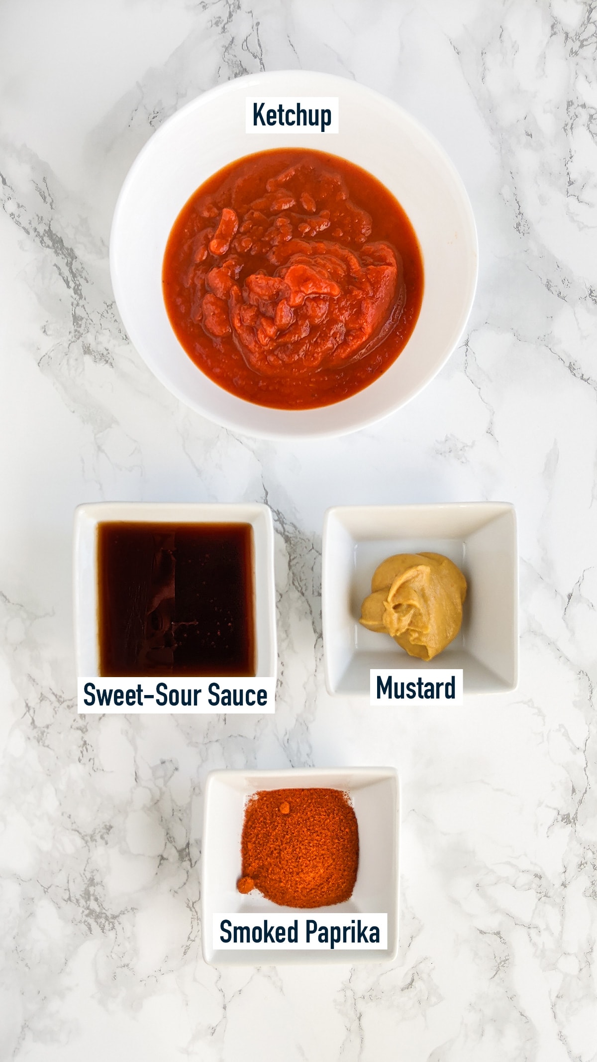 Ketchup, sweet-sour sauce, mustard, smoked paprika on a marble table.