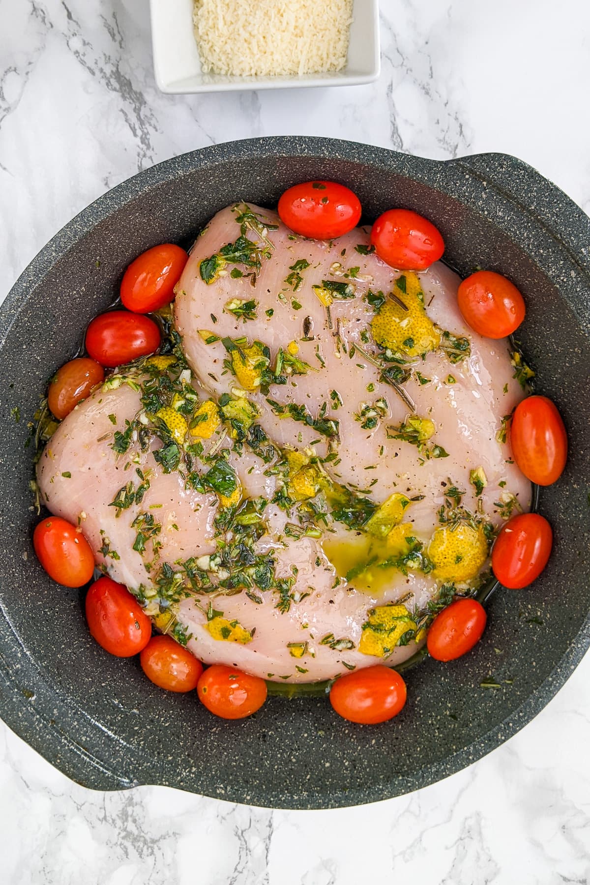 Cherry tomatoes near chicken breast marinated with Italian spices.