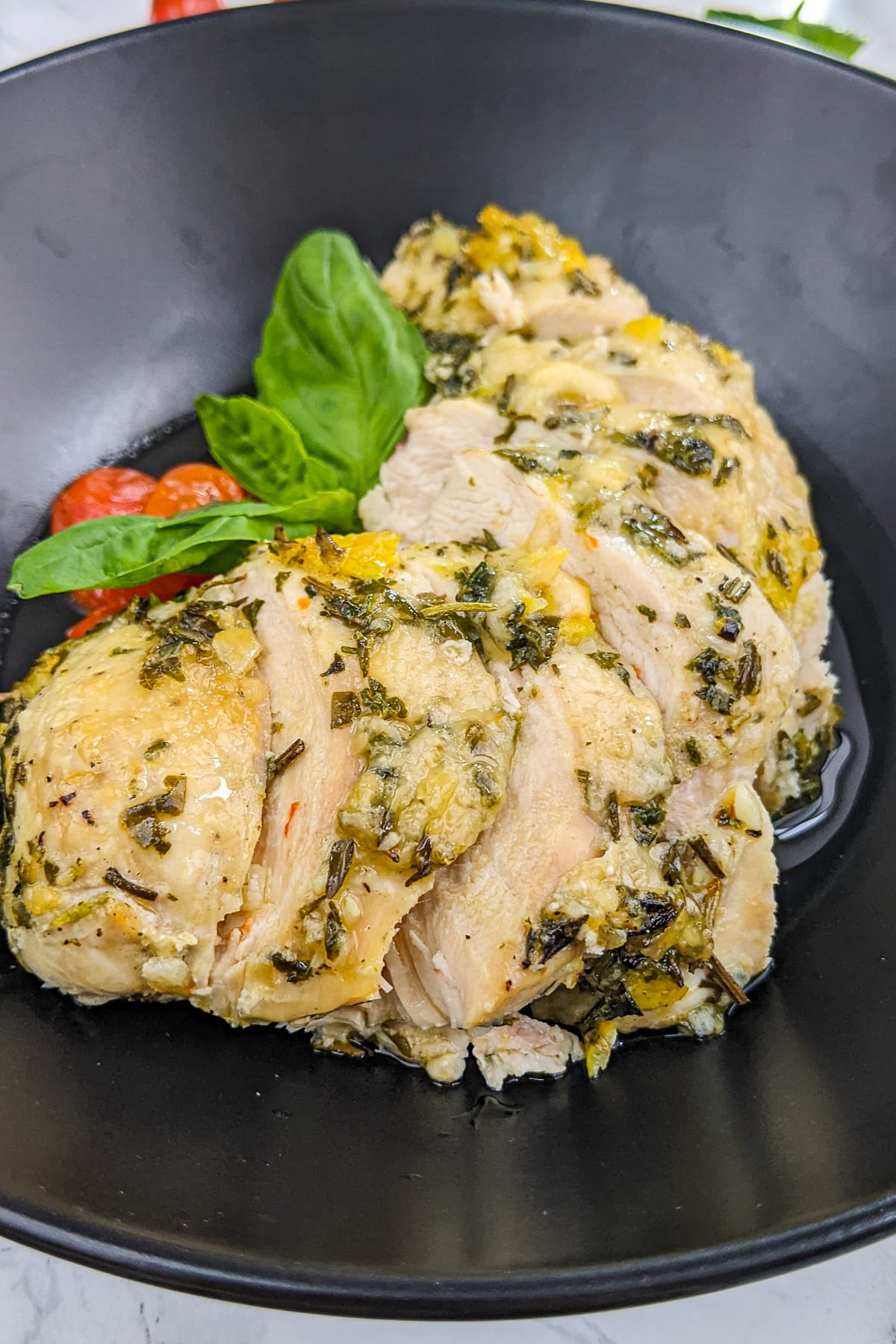 Close look of juicy chicken breast with basil leaf and cherry tomatoes.