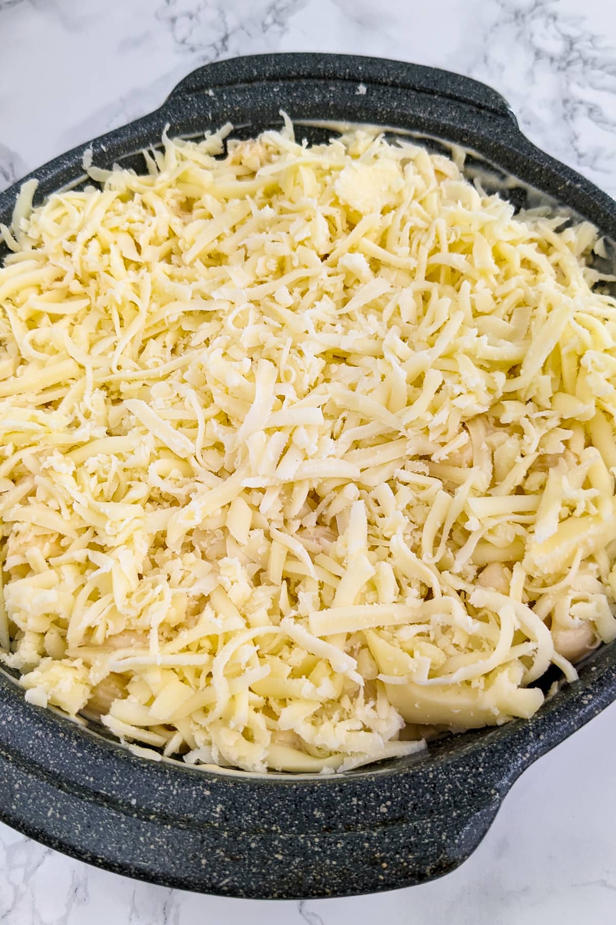 Gray casserole with shredded mozzarela cheese over mac and cheese.