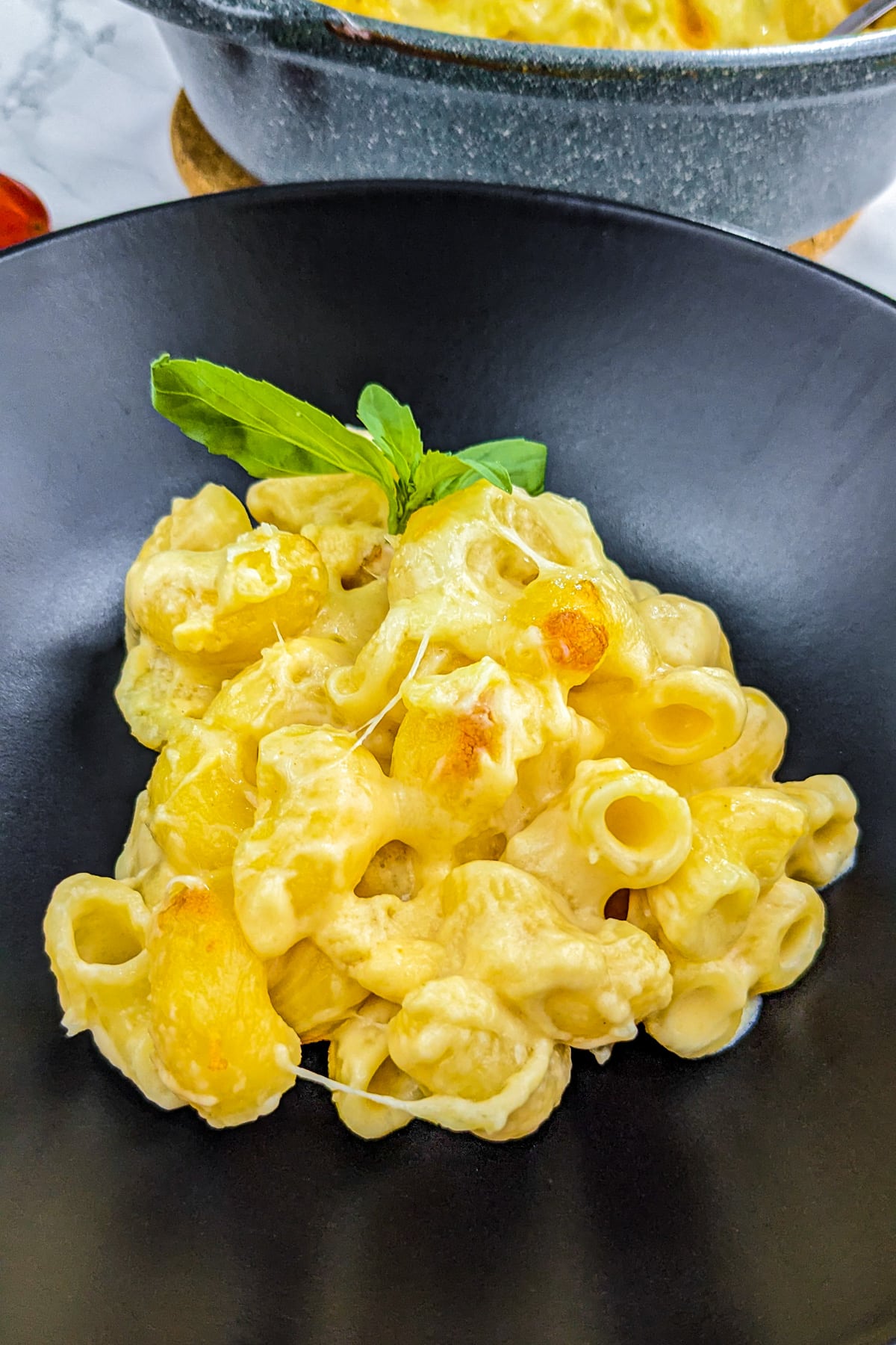 Close view of creamy mac and cheese on a black plate.