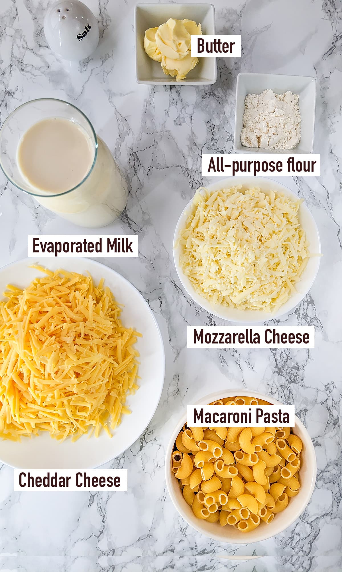 Macaroni pasta near cheddar, mozzarella, flour, butter and evaporated milk.