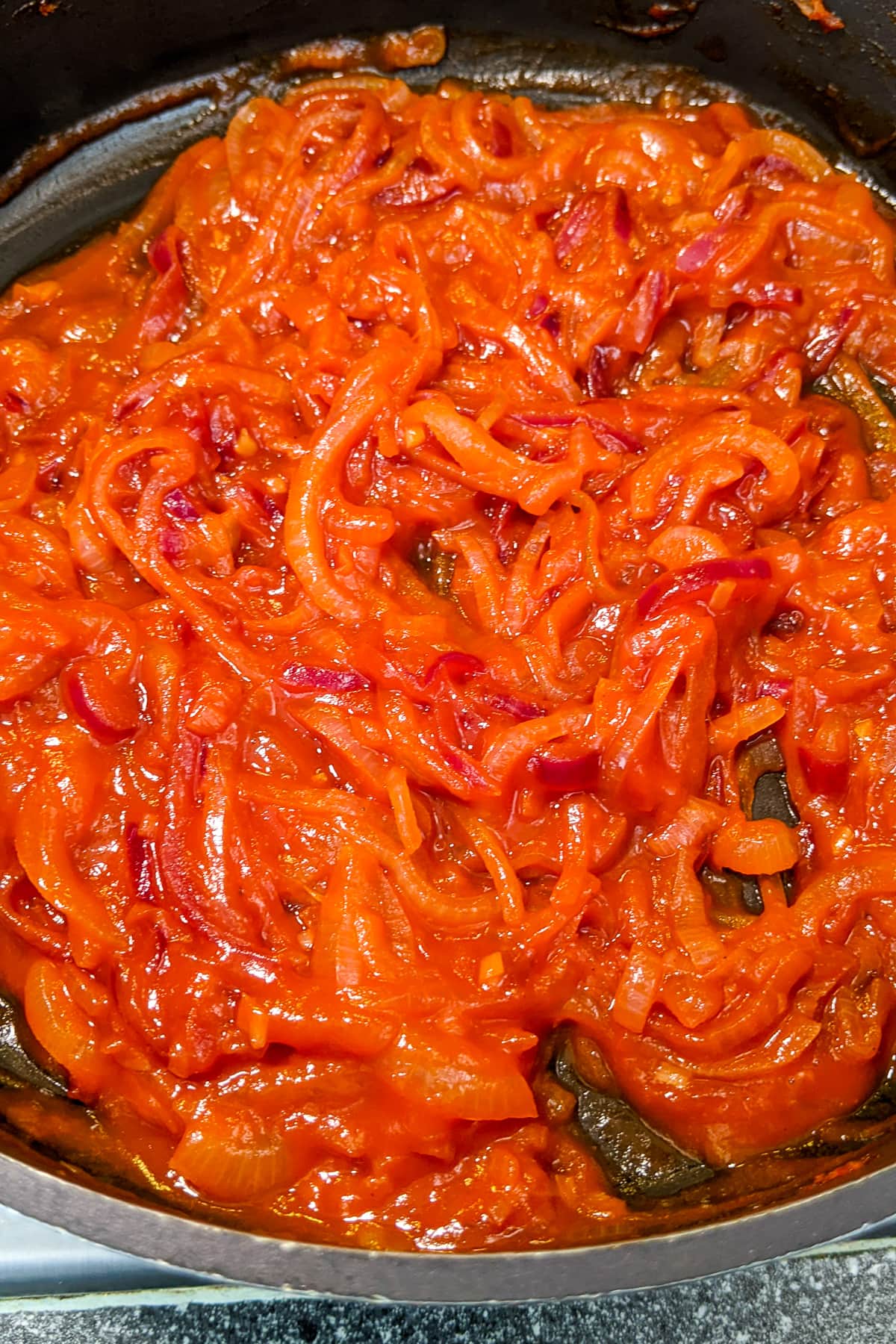 Close look of flavorful onions in red sauce.