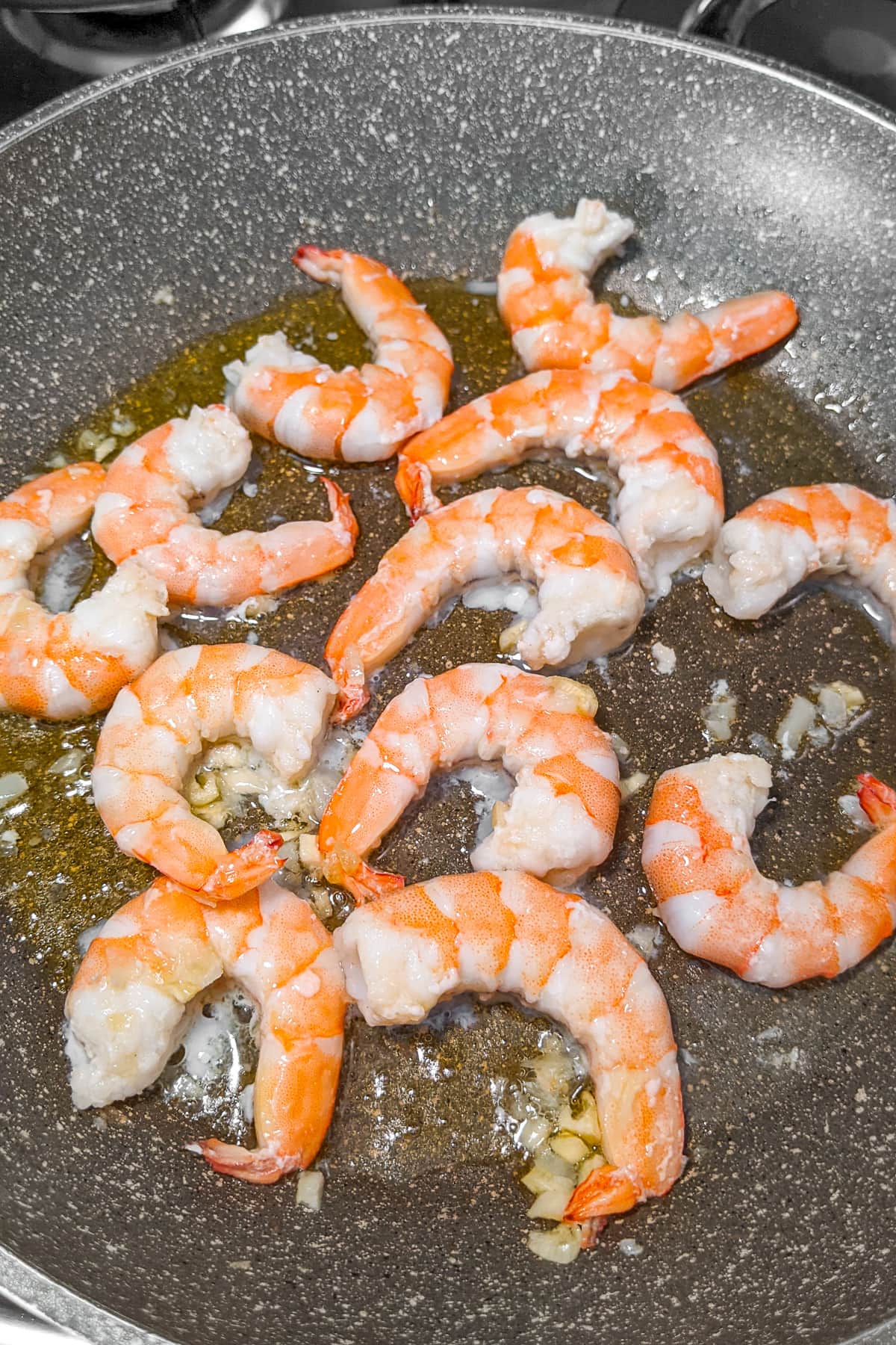 Frying prawns in a frying pan with olive oil and garlic.