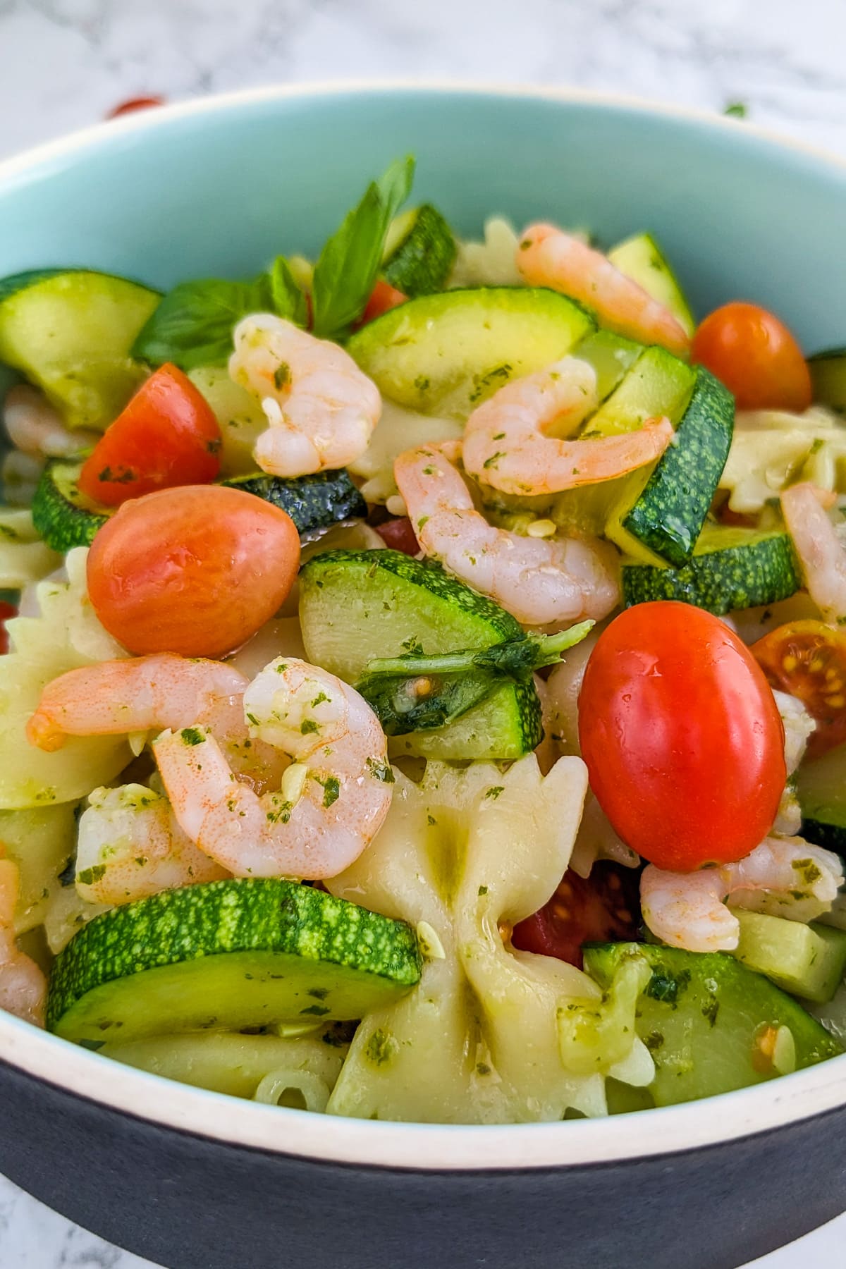Close look of shrimp pasta salad with cherry tomatoes, and salad dressing.