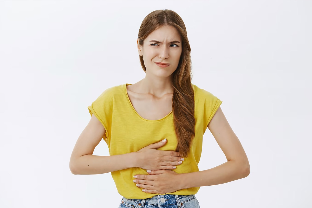 A girl with yellow t-shirt feeling stomach pain.