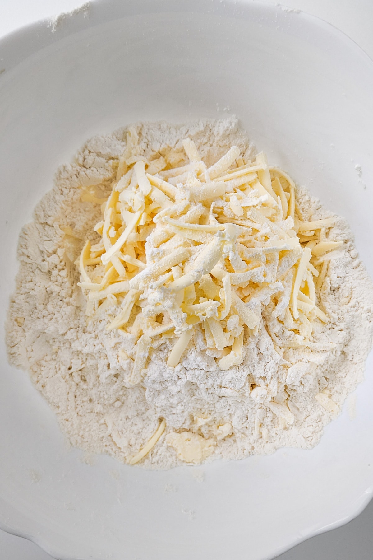 Shredded butter mixed with flour in a deep bowl.