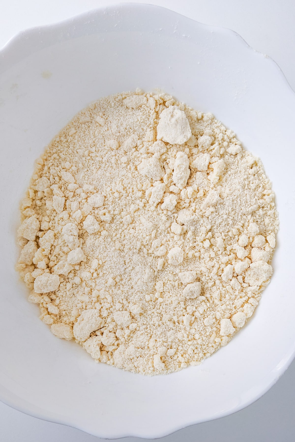 White deep plate with mixed ingredients for sugar cookies dough.