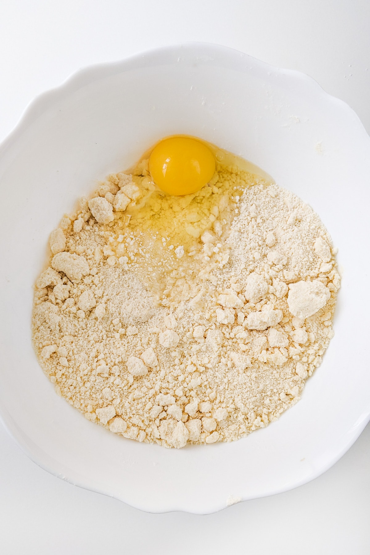 An raw egg over dried sugar cookies dough ingredients.