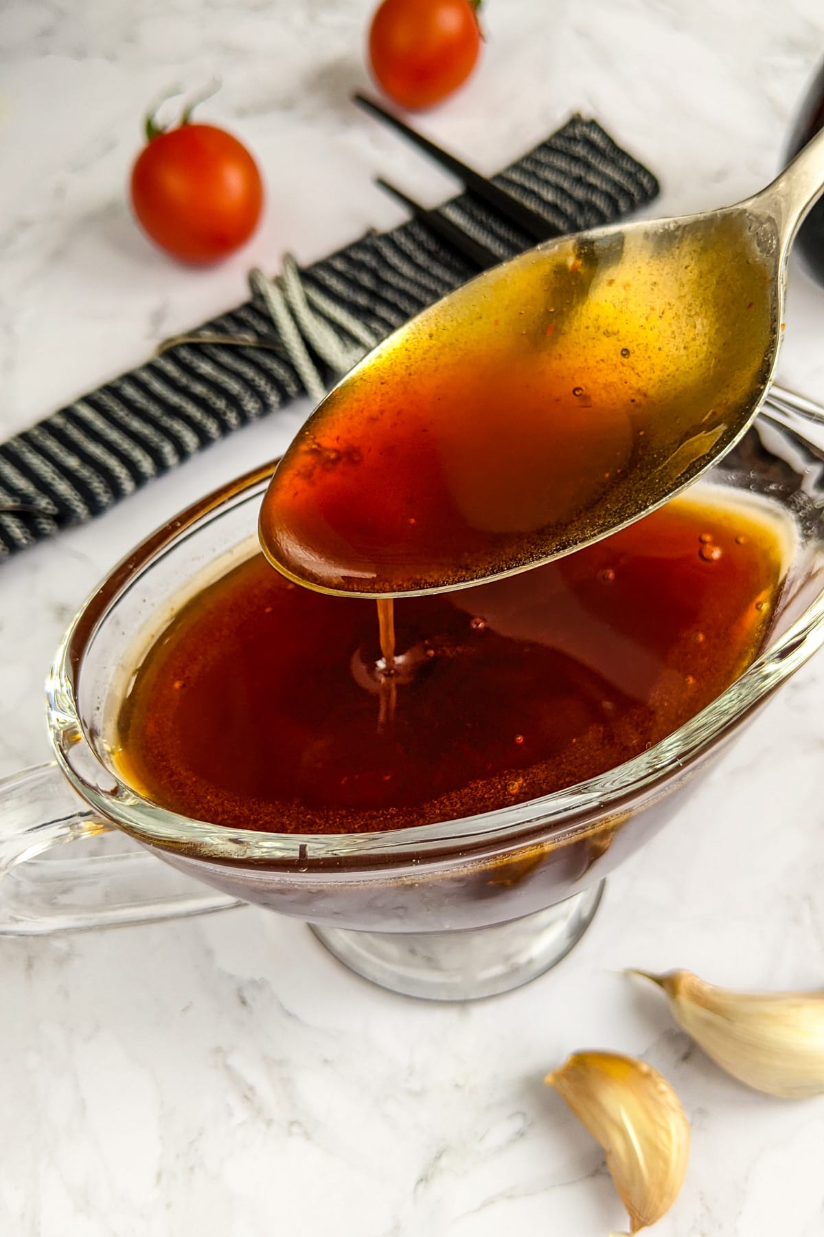 Pouring sweet and sour sauce from a tablespoon in a transparent bowl.