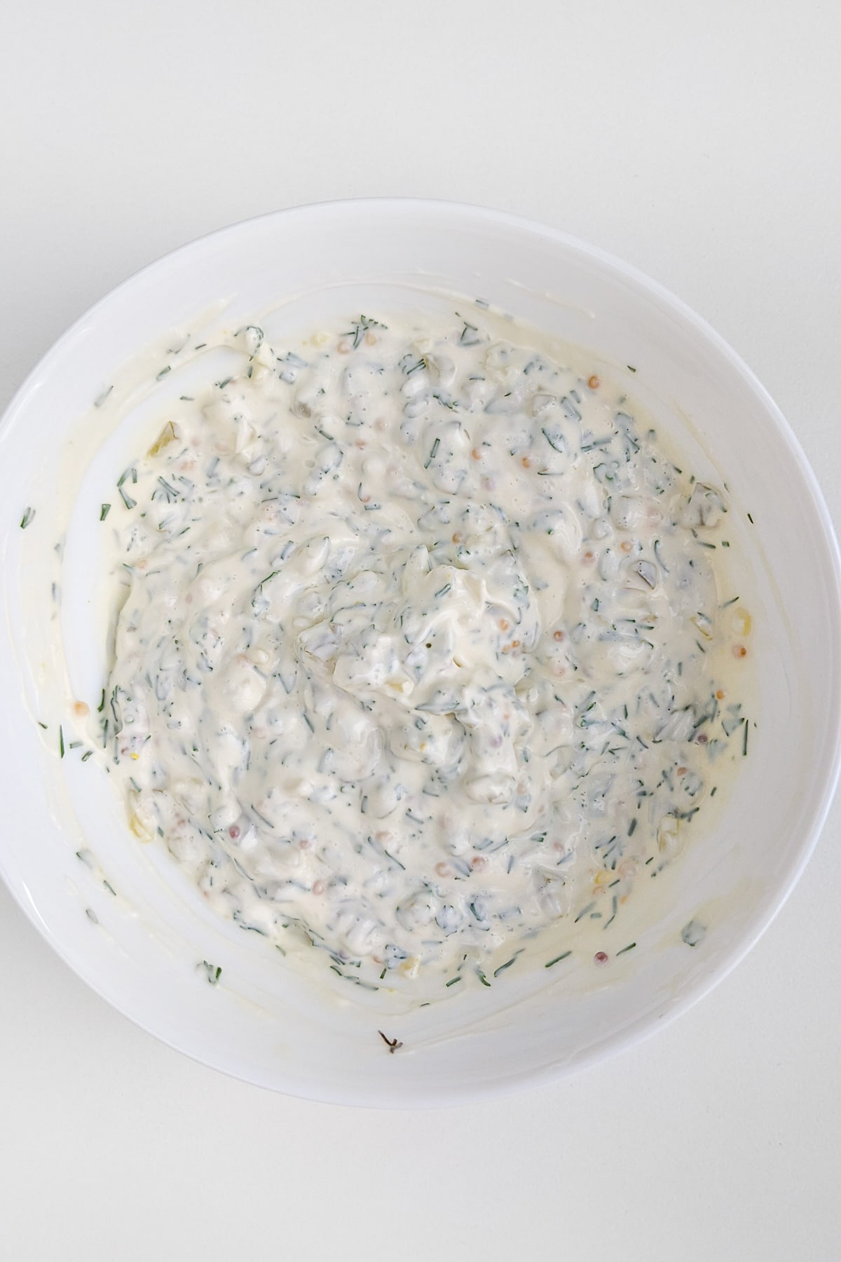 Top view of white plate with mixed homemade tartar sauce.