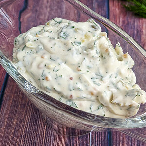Close view of tartar sauce on a wooden table background.