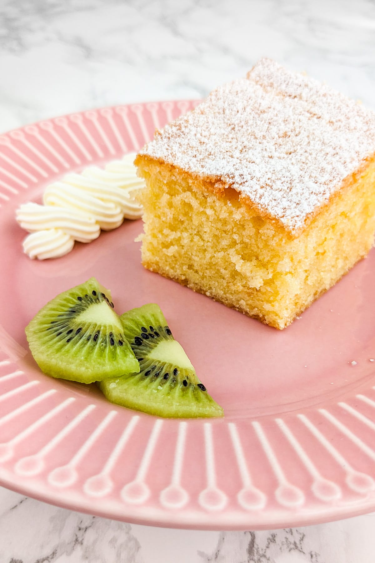 A close look of a a piece of air fryer sponge cake on a pink plate.
