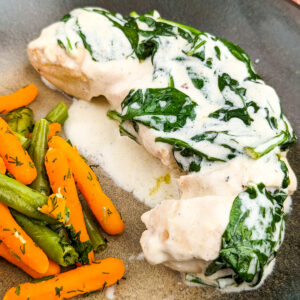 Close look of chicken breast a la king with spinach, carrots and peas.
