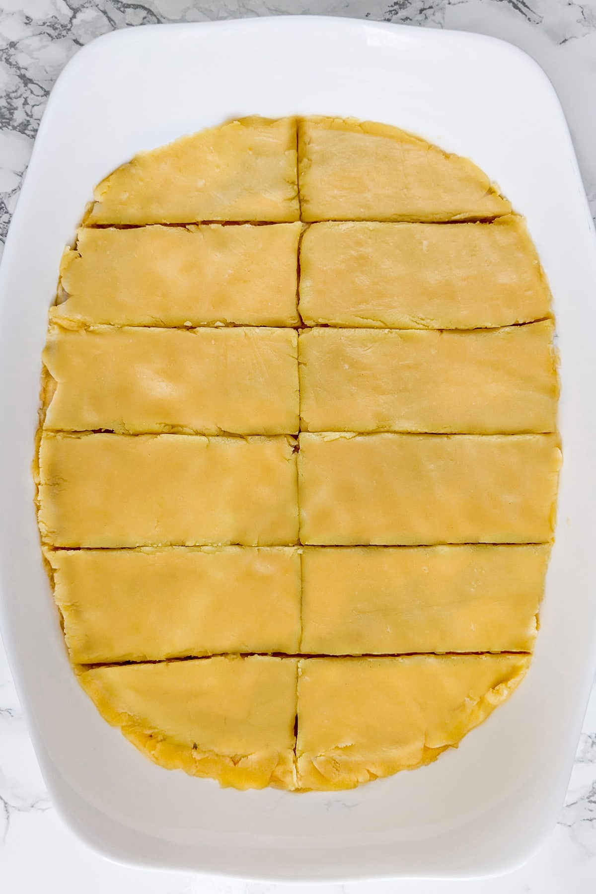 Top view of sliced apple slice cake on a white marble table.