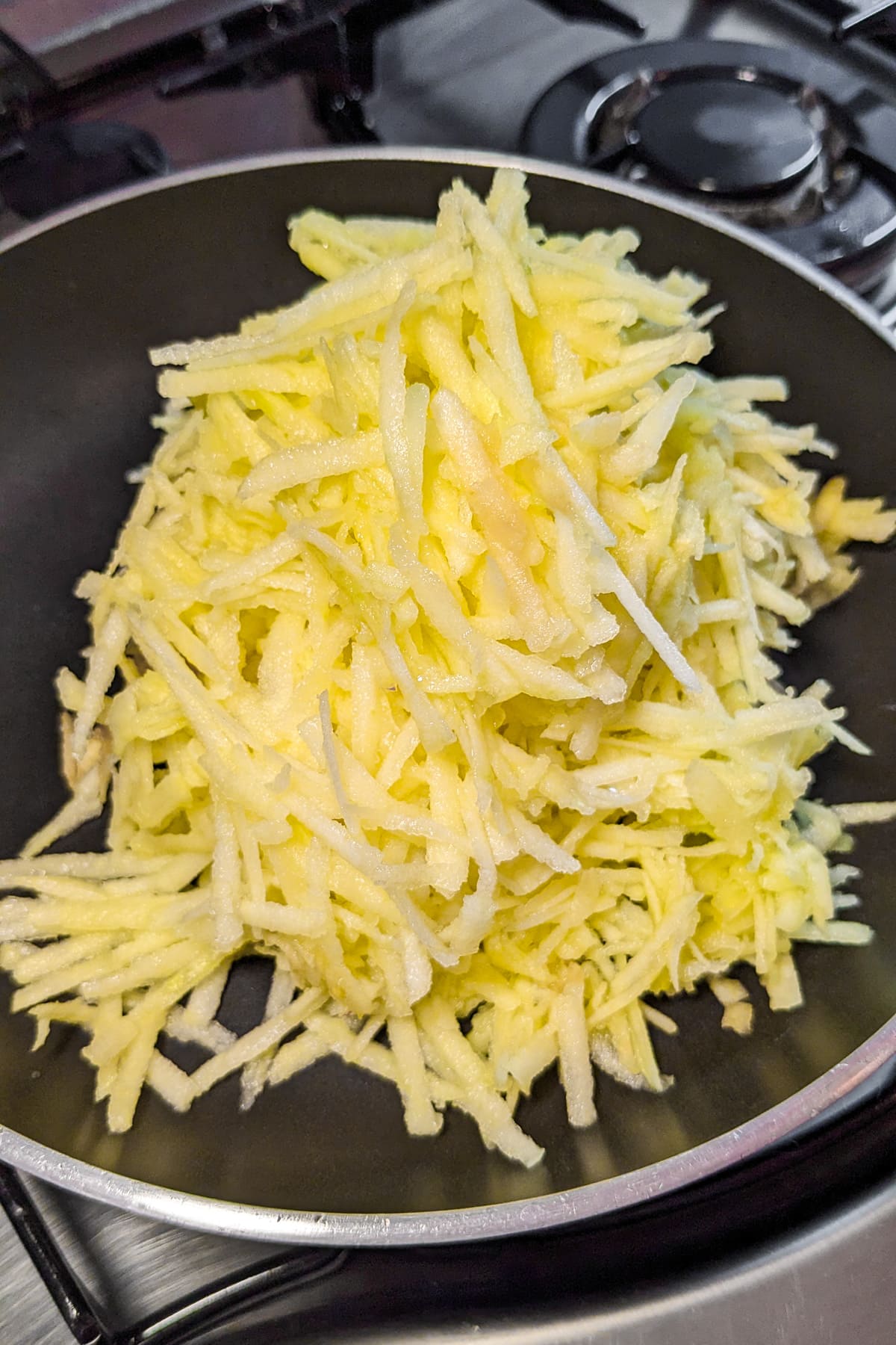 Grated apples in a frying pan on the stove.