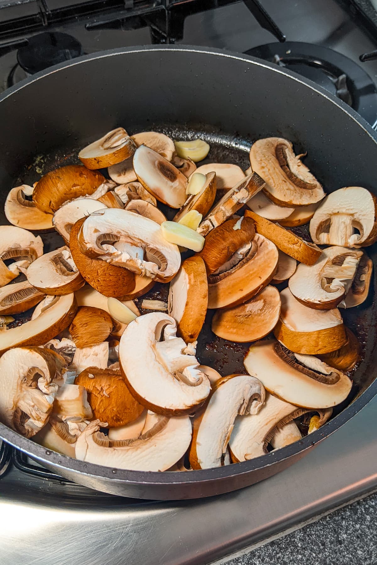 Close look of sliced mushrooms in a large saucepan.