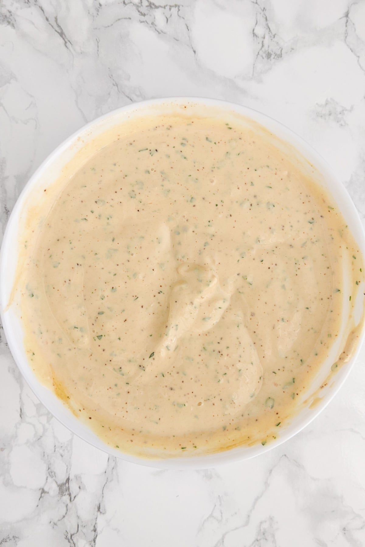 Top view of a white plate full of bistro sauce on a white table.