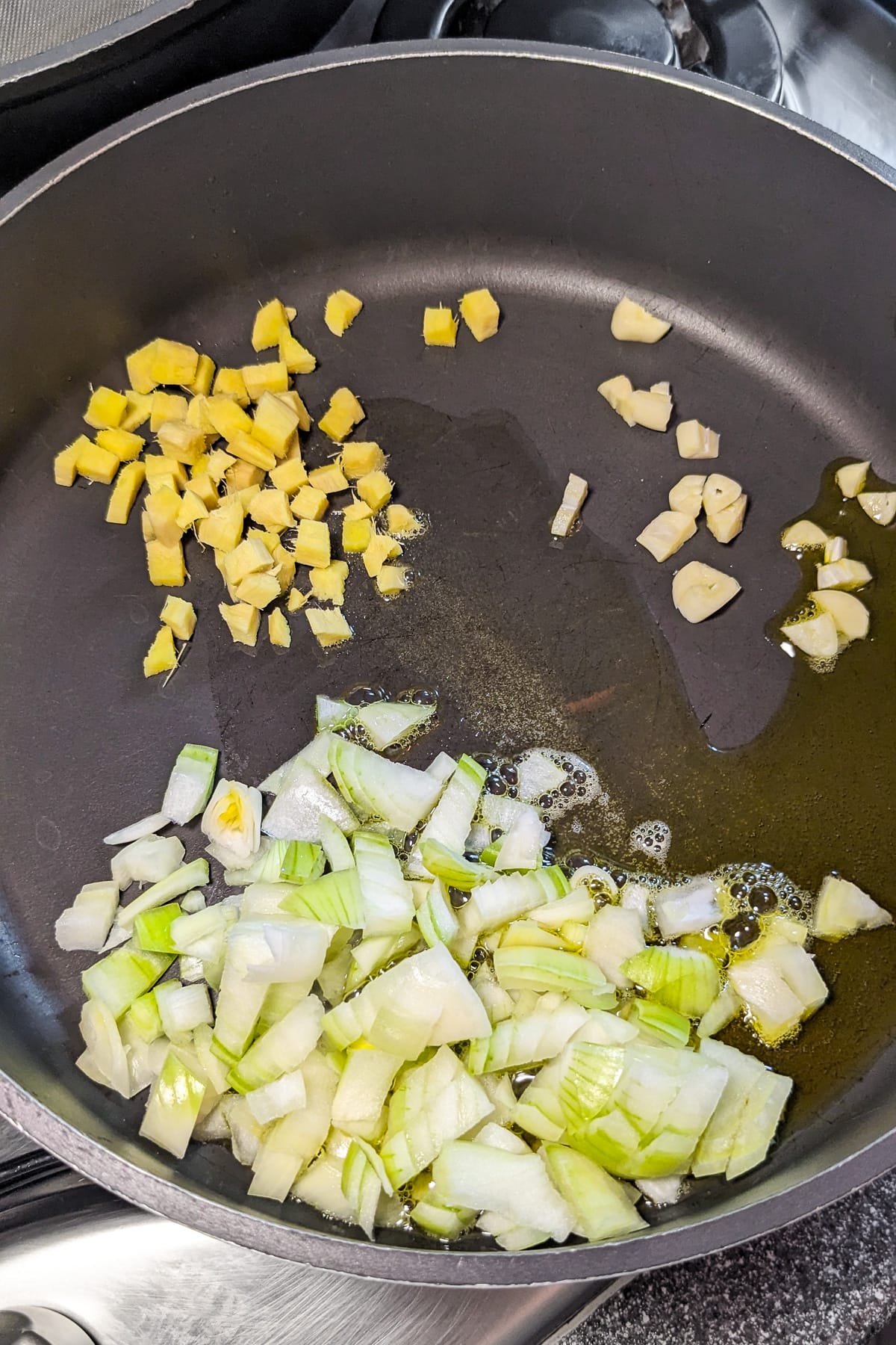 Frying pan with chopped onions, garlic and ginger in olive oil.