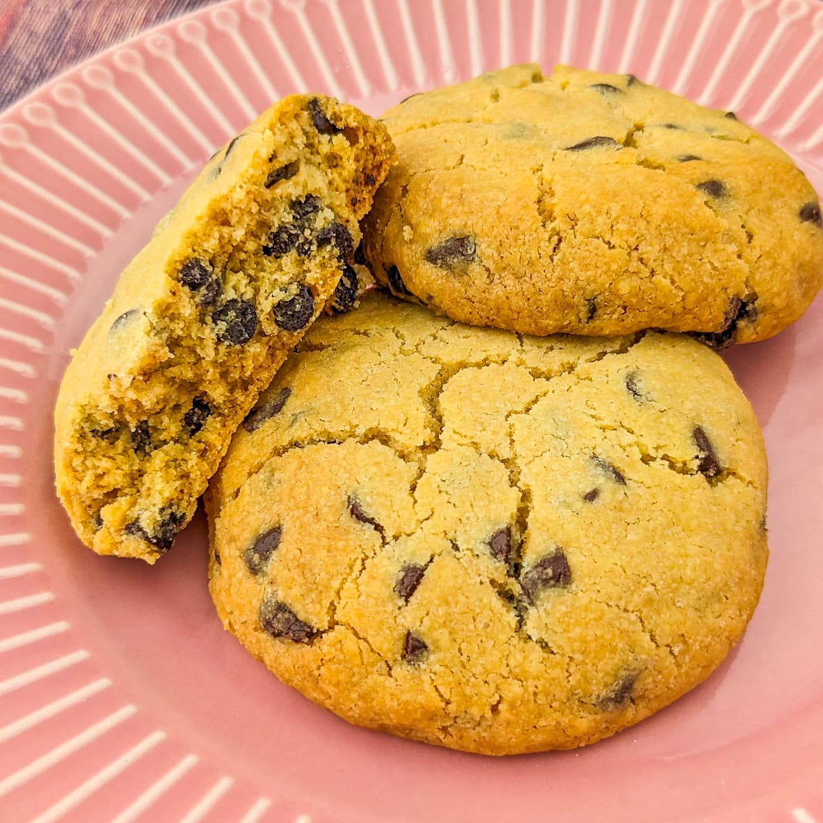 Close look of 2 and halve chocolate chip cookies on a pink plate.