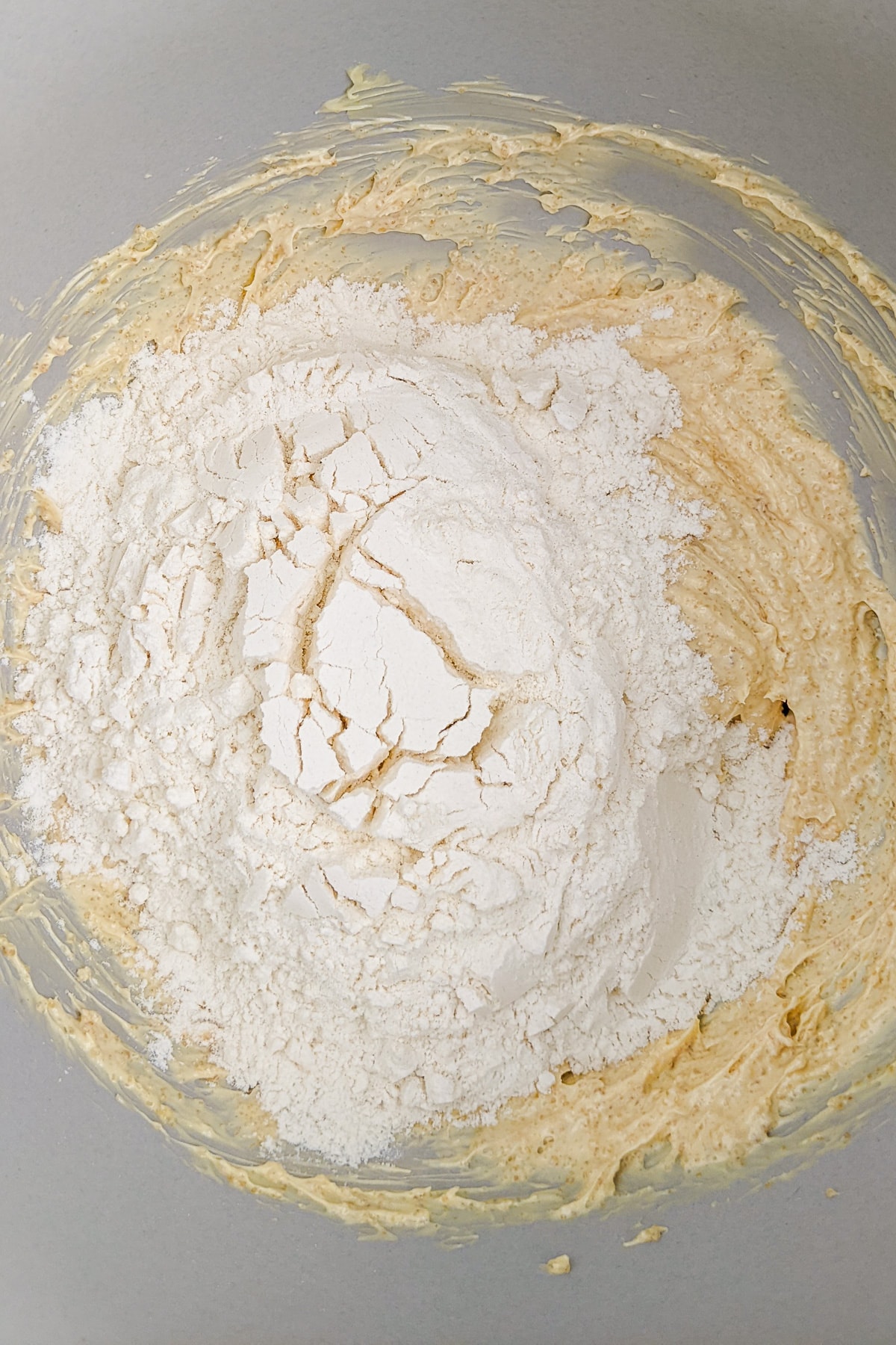 Adding all-purpose flour over a mix of butter and sugar.