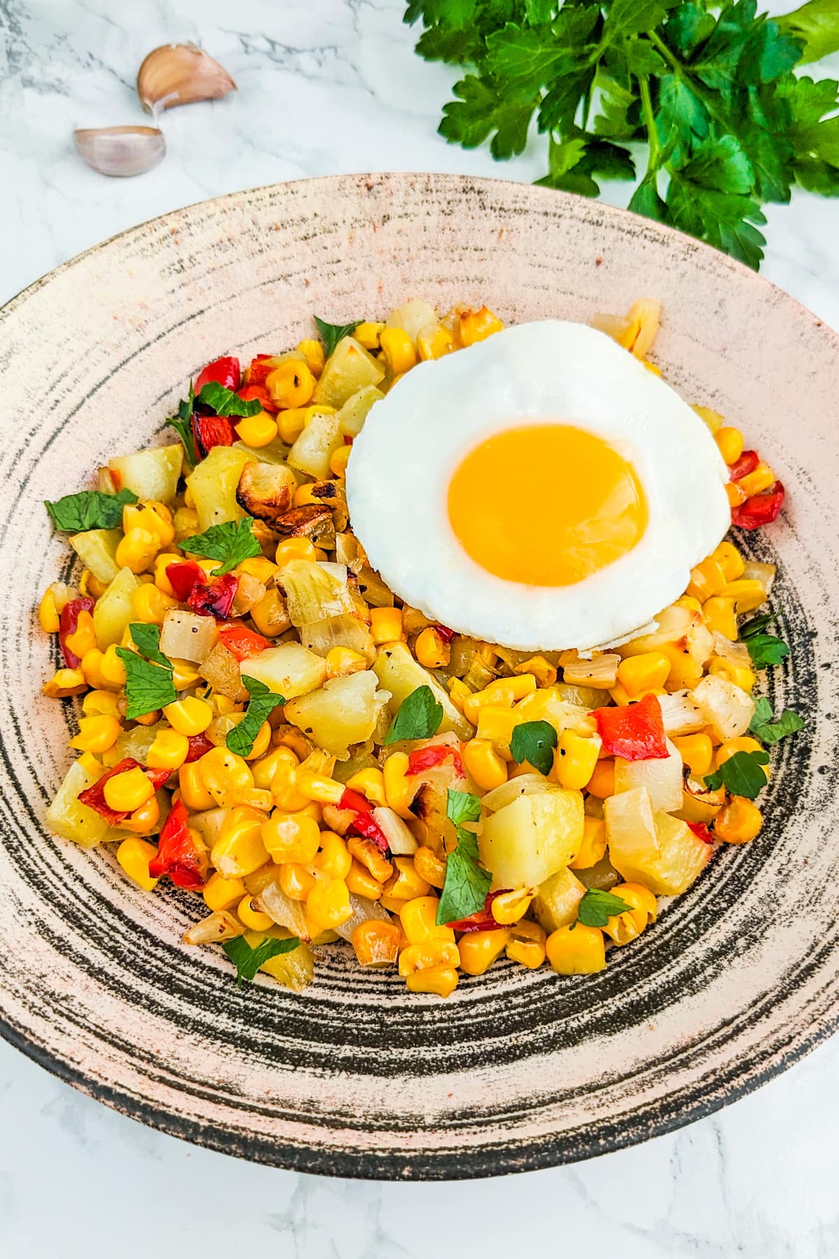 Vintage plate with corn hash, a fried egg, garlic and parsley.