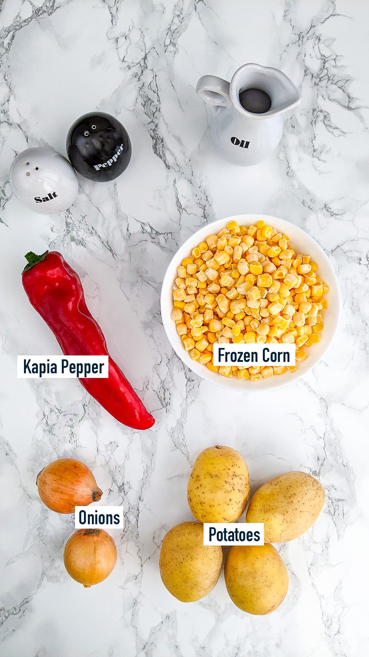 Frozen corn, potatoes, onions and kapia pepper on a marble table.