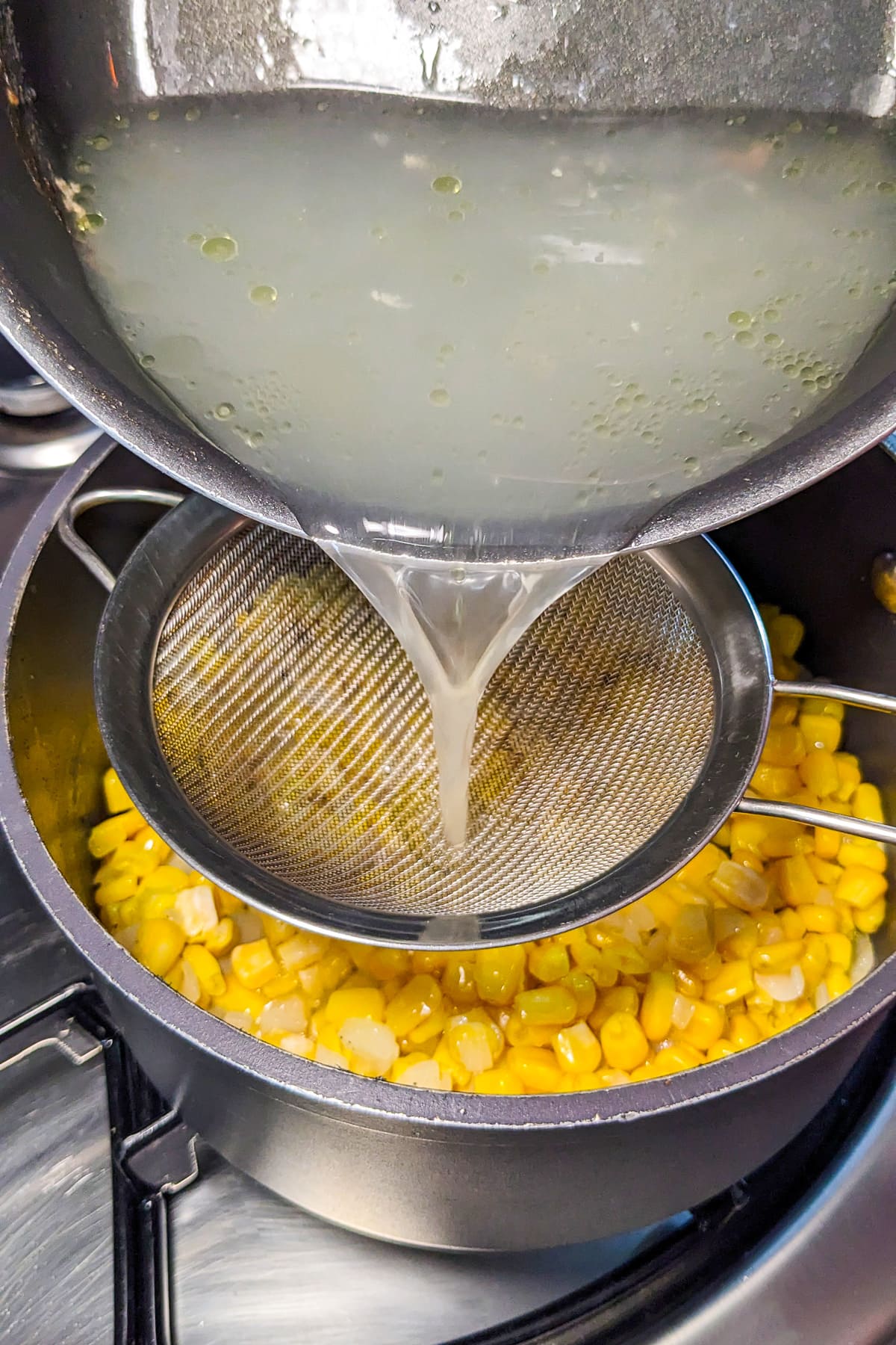 Pouring chicken broth over cooked corn.