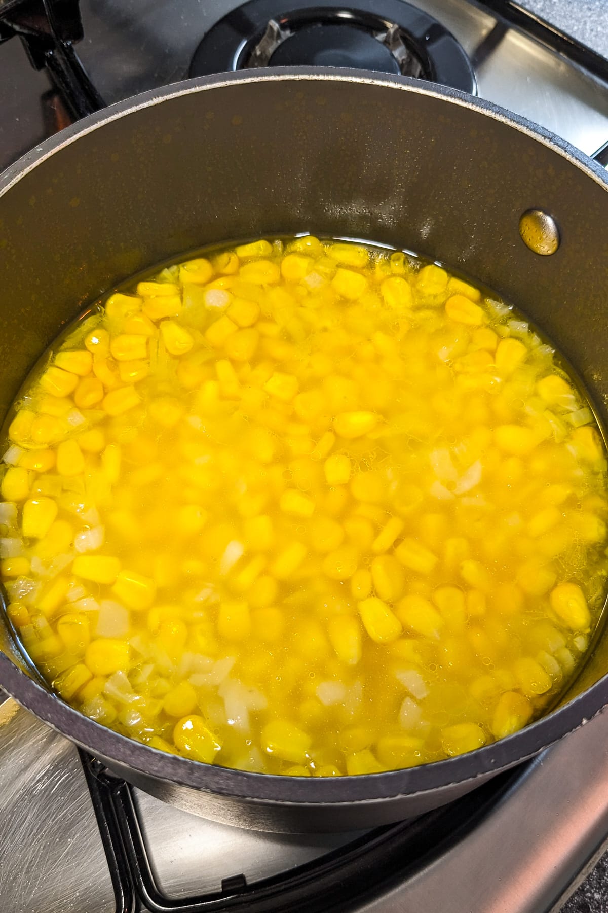 Cooked corn in water in a saucepan on the stove.