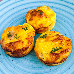 Close look of bacon and cheese muffins on a blue plate.