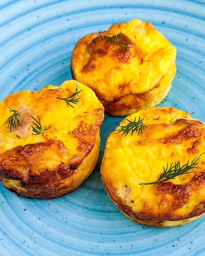 Close look of bacon and cheese muffins on a blue plate.