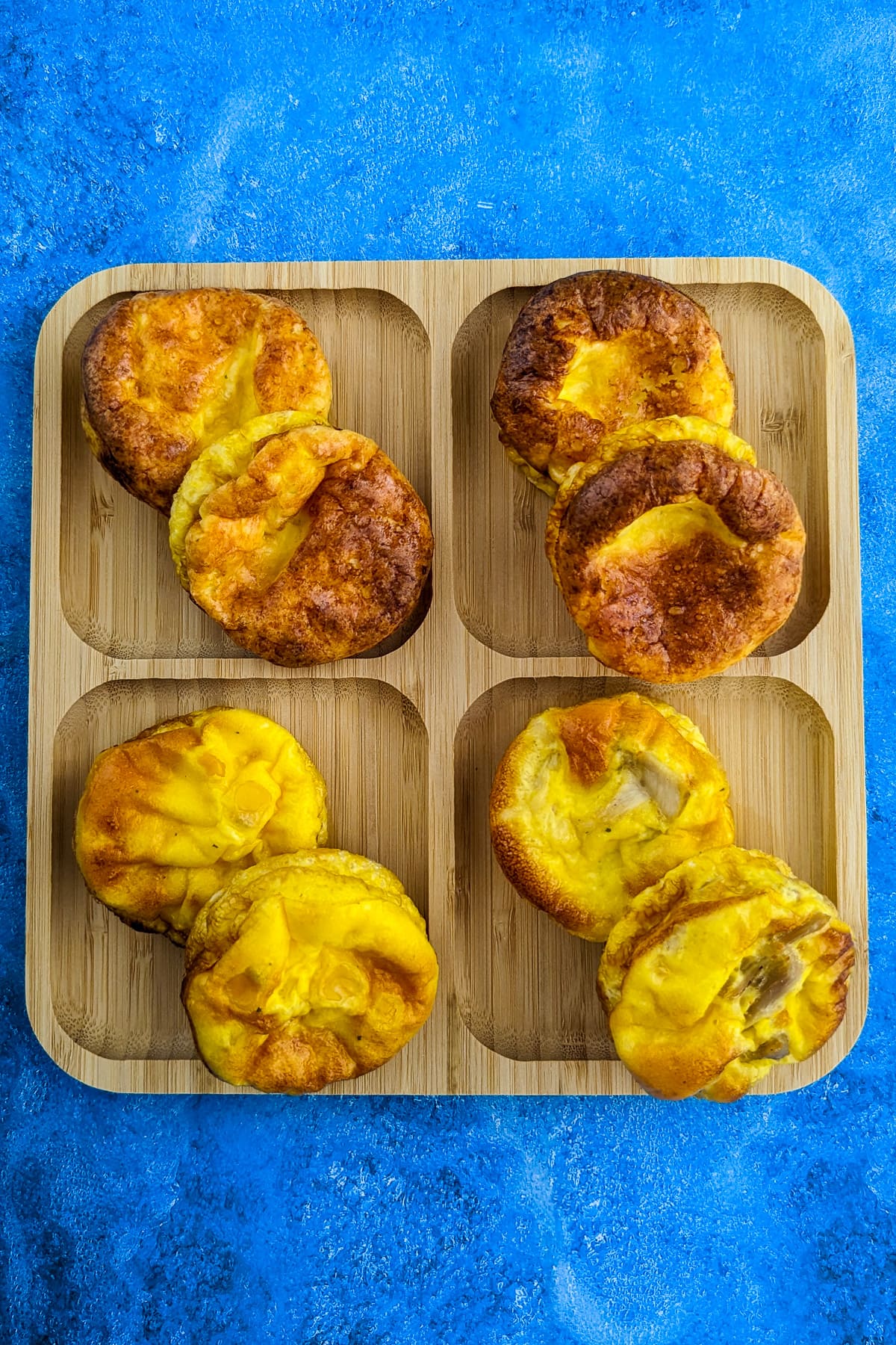 4 variations of egg muffins for kids on a wooden plate.
