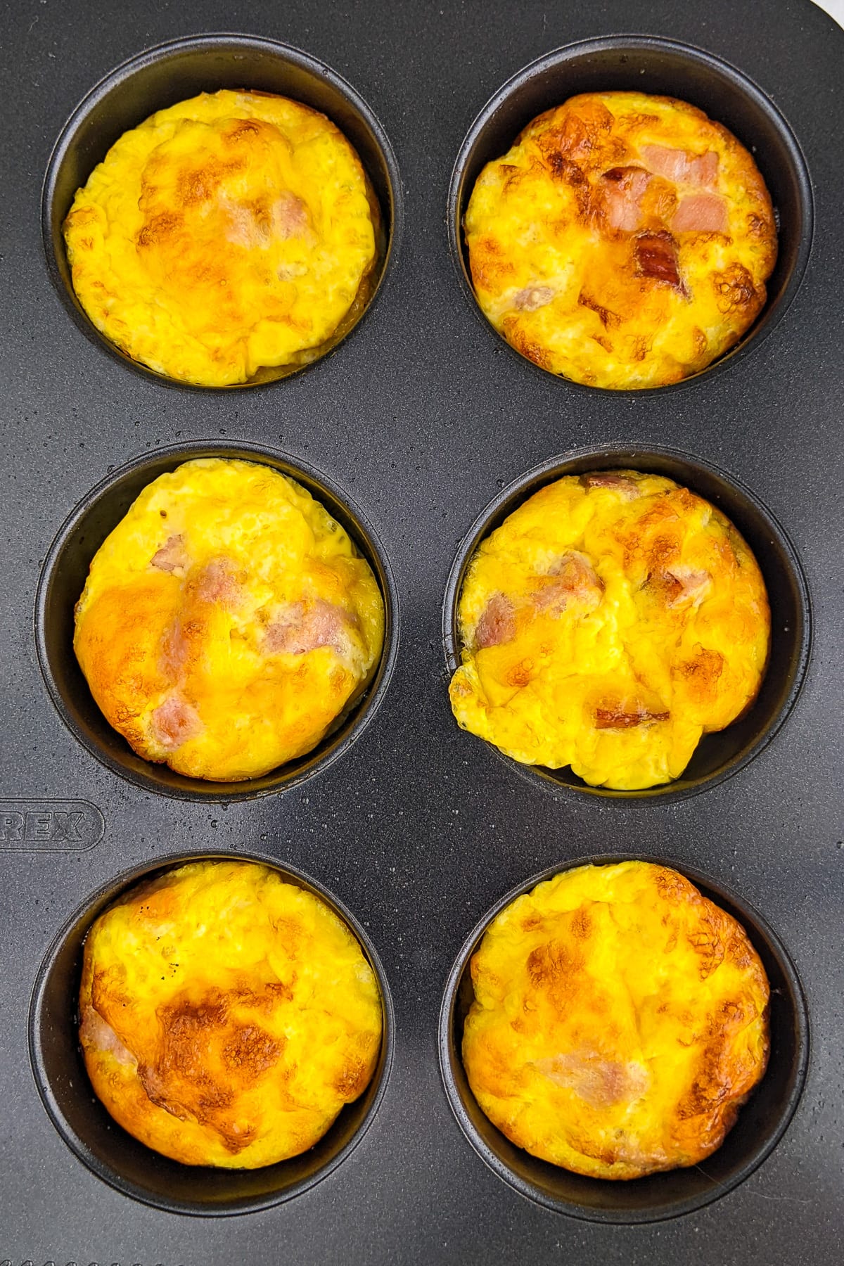 Top view of a metal muffins mold with 6 cheese muffins.