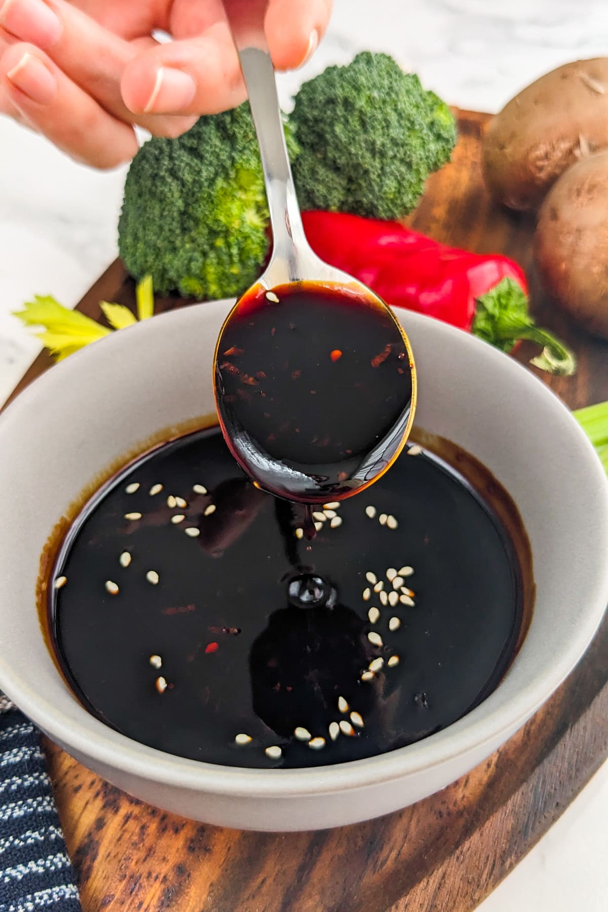 Woman hand with a teaspoon pouring soy sauce.