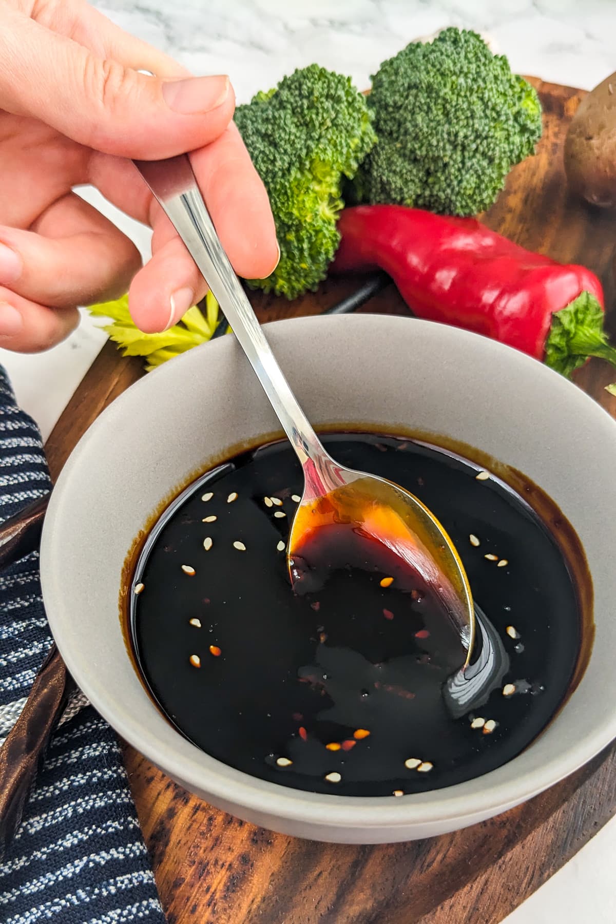 Woman hand with a teaspoon pouring soy sauce.