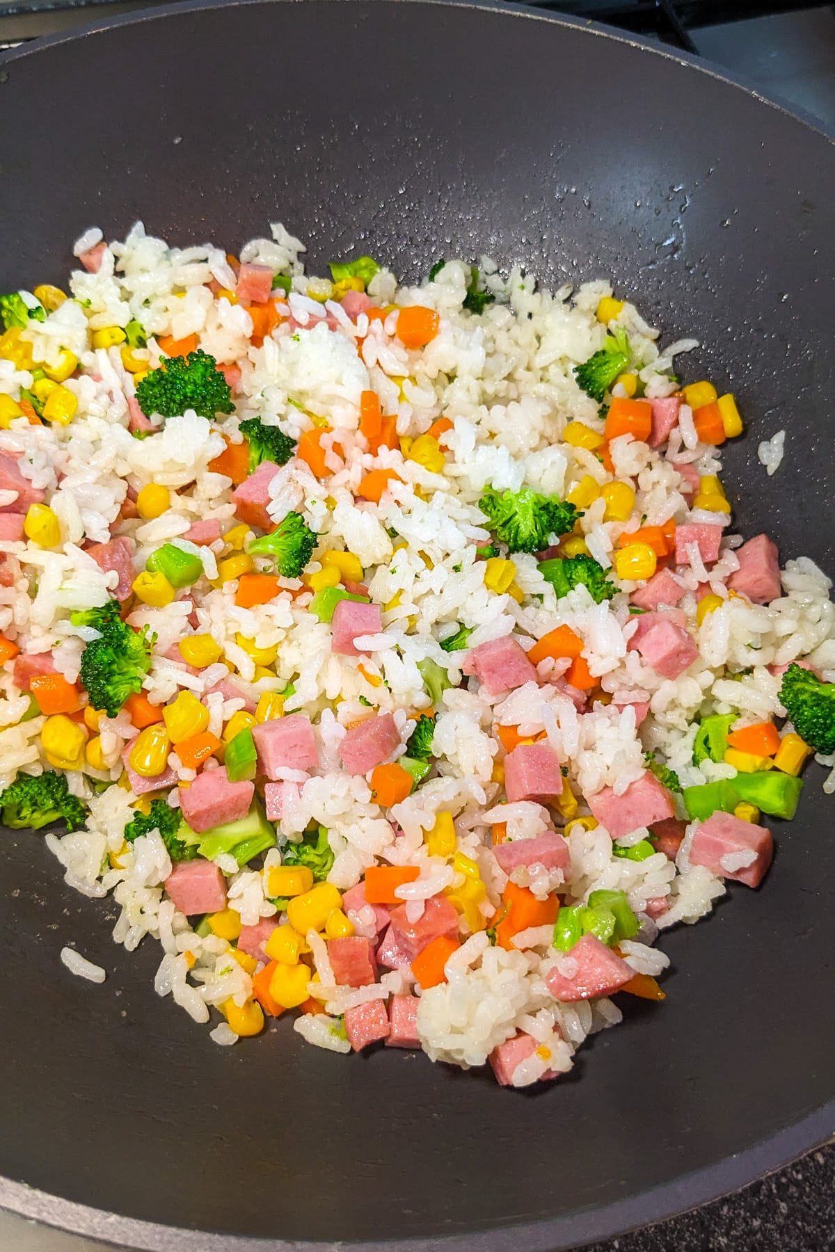 Leftover rice with veggies, luncheon meat in a wok.