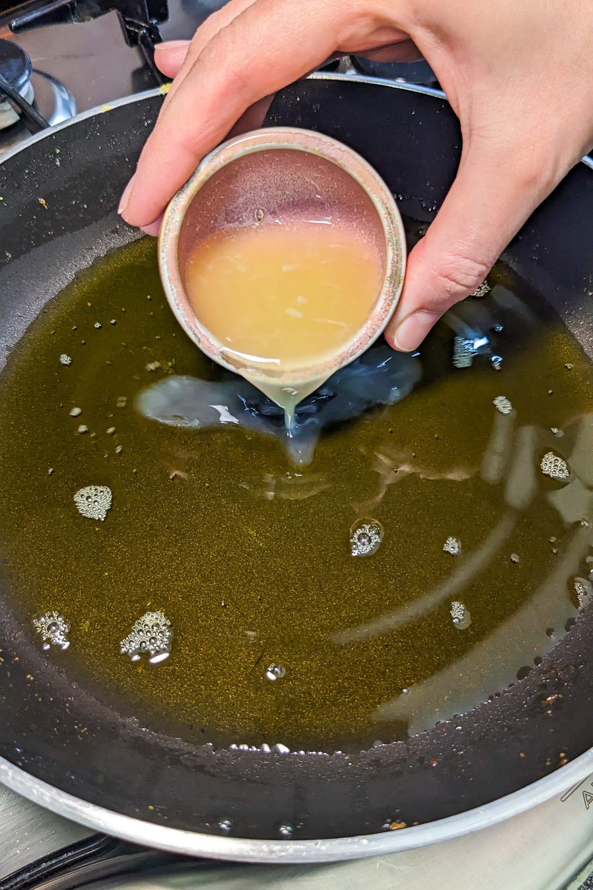 Pouring lemon juice in a frying pan.