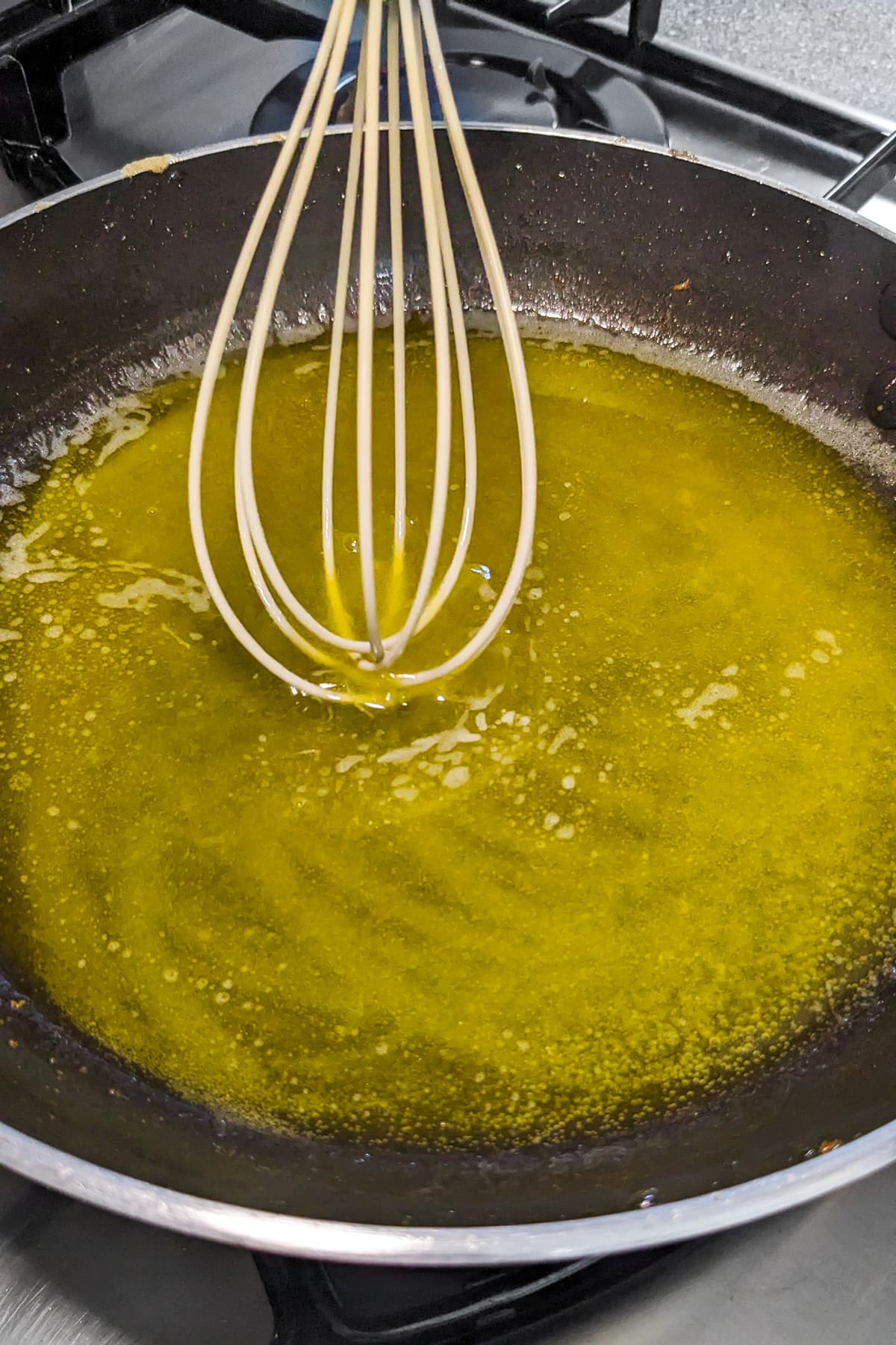 A whisk over a wok with meuniere sauce.